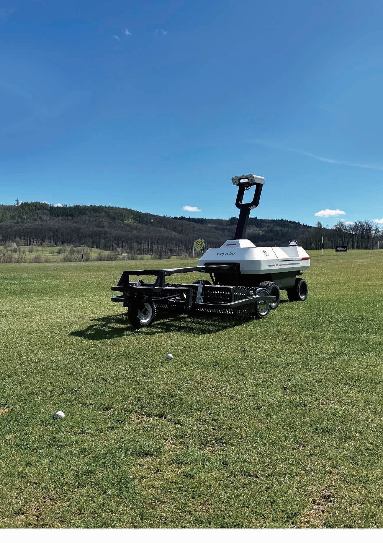 WayRobo autonomous golf ball collection robot operating on a UK driving range at dusk